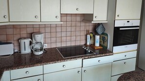 A kitchen with white cabinets, a built-in oven, a coffee maker, and a kettle. - St Cyprien: Calm and gentleness on the edge of the lagoon (Saint-Cyprien)