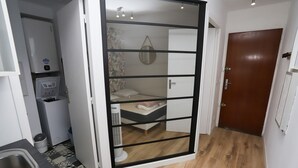 A compact room with a sliding door leading to a bedroom. A small kitchenette is visible with a sink and a compact refrigerator. The room has a wooden floor and a door with a handle. - St Cyprien, a gem on the port, everything within easy reach (Saint-Cyprien)