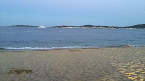 A beach with a chair and a towel, a boat in the distance, and a clear sky. - Gulf of St Tropez. Close to beaches. Property with swimming pool. Ideal for large groups (Grimaud)