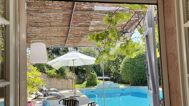 A view from a window of a poolside area with a table and chairs, a covered seating area, and a swimming pool. - Gulf of St Tropez. Close to beaches. Property with swimming pool. Ideal for large groups (Grimaud)