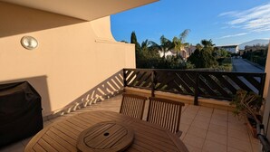 A round wooden table with chairs on a balcony with a view of a residential area and trees. - St Cyprien Sunny retreat with pool access (Saint-Cyprien)