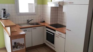 A compact kitchen with white cabinets, a sink, a stove, and a window. - St Cyprien Sunny retreat with pool access (Saint-Cyprien)