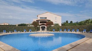 A swimming pool with blue water, surrounded by lounge chairs and a building in the background. - St Cyprien Sunny retreat with pool access (Saint-Cyprien)