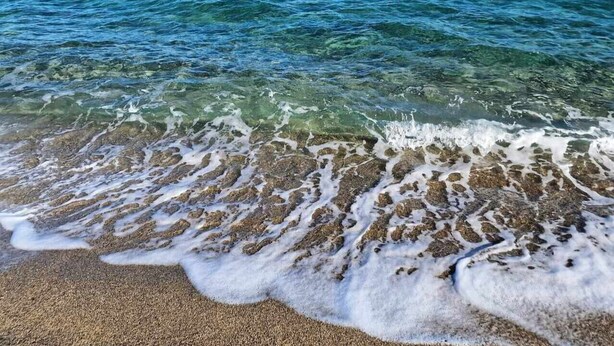 A beach with clear water and visible sand.