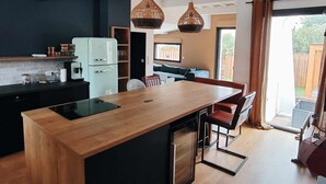 A modern kitchen with a wooden island, black appliances, and hanging wicker pendant lights.