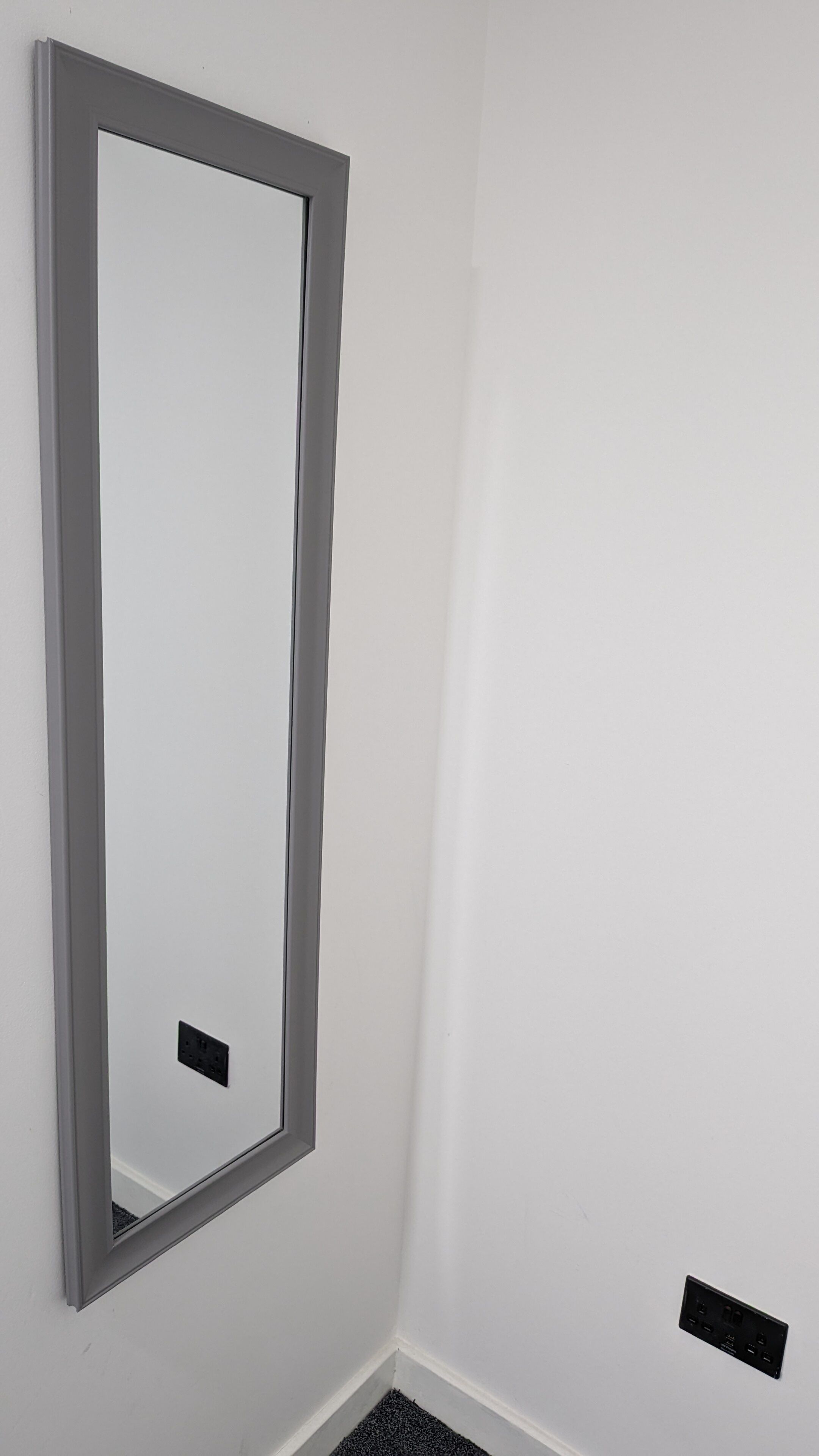Une porte avec un miroir et une prise de courant sur le mur.