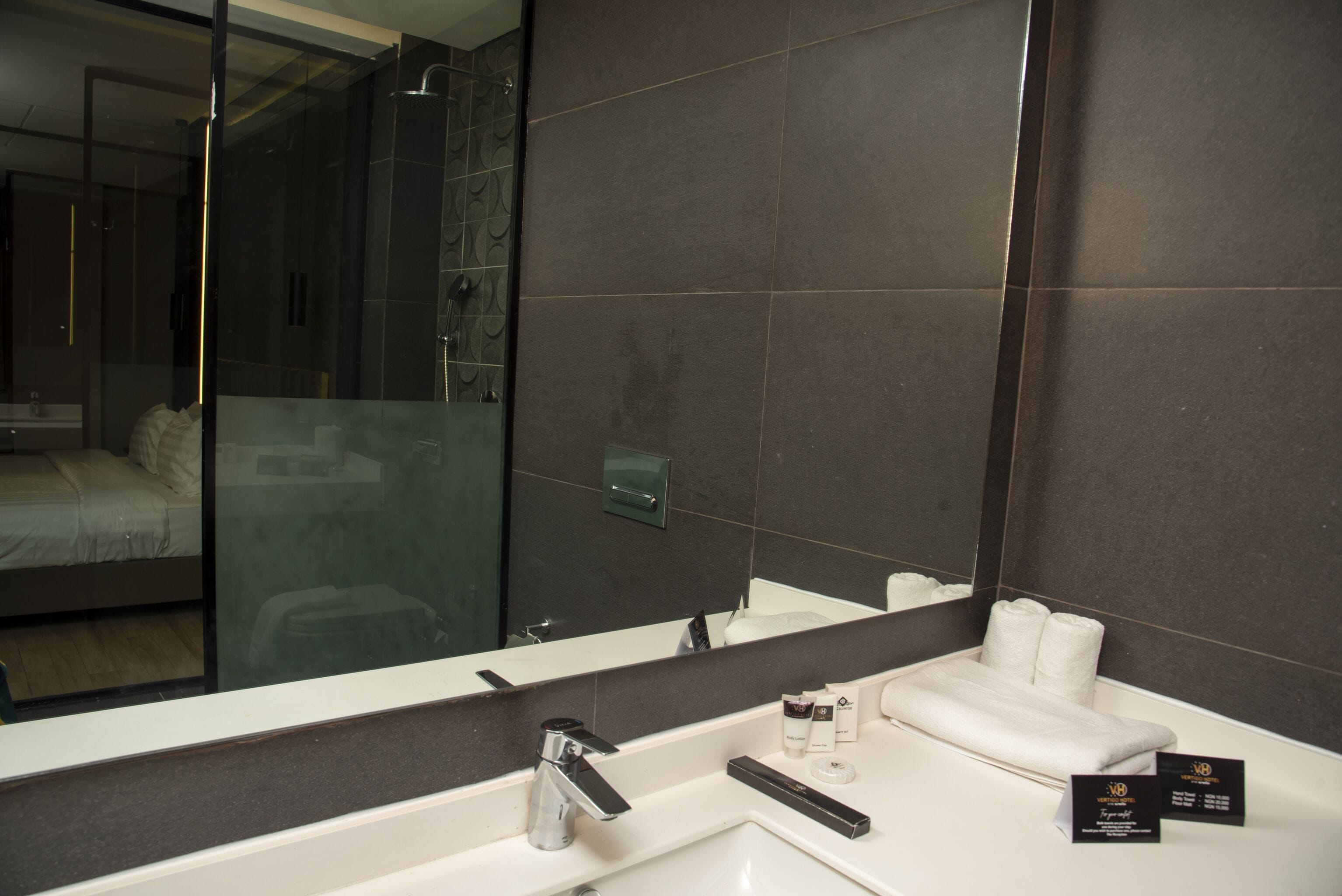 Un baño moderno con un espejo grande, un lavabo blanco y una cabina de ducha de vidrio.