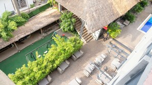 Zona de piscina en la azotea con techo de paja, sillas de descanso y una piscina pequeña.