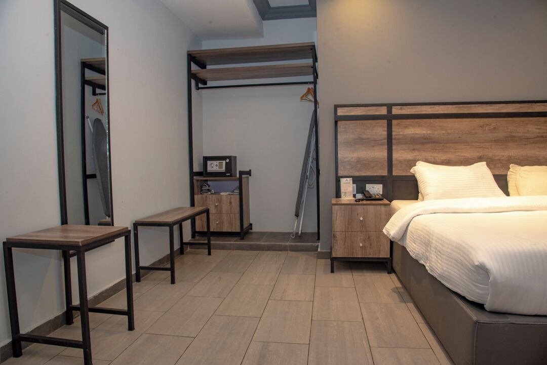 A bedroom with a bed, bedside tables, a wardrobe, and a hanging rack.