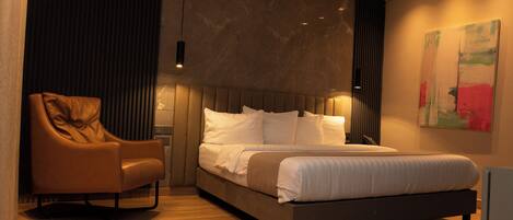 A modern bedroom with a large bed, a leather armchair, and a minimalist decor.