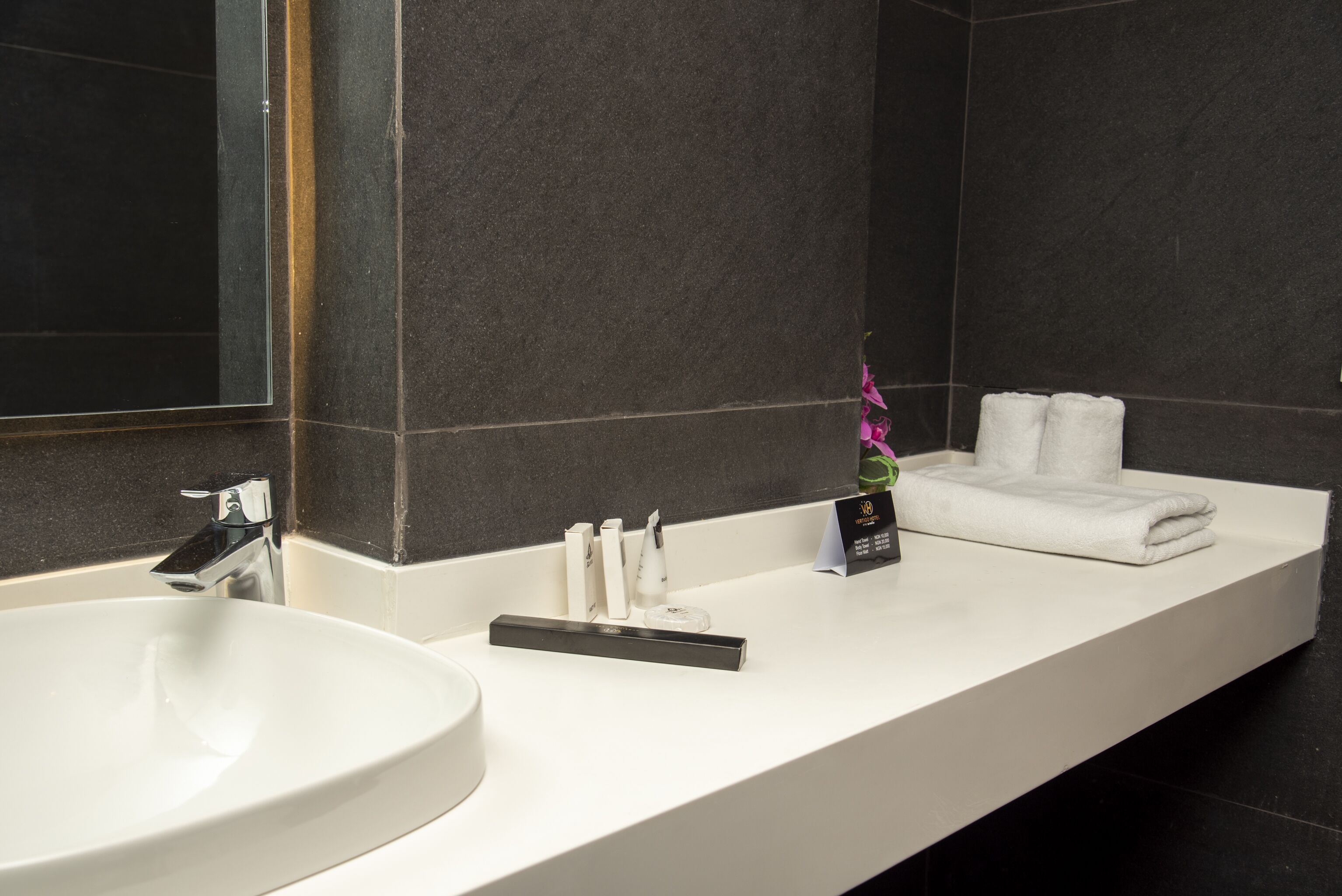 A modern bathroom with a large white sink, a mirror, and a towel rack.