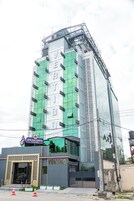 Un edificio de varios pisos con fachada verde y blanca, un cartel de casino visible y una entrada con puerta de rejas.
