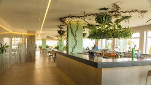Un área de bar moderna con una barra de mármol, plantas colgantes y vistas a la ciudad a través de amplios ventanales.