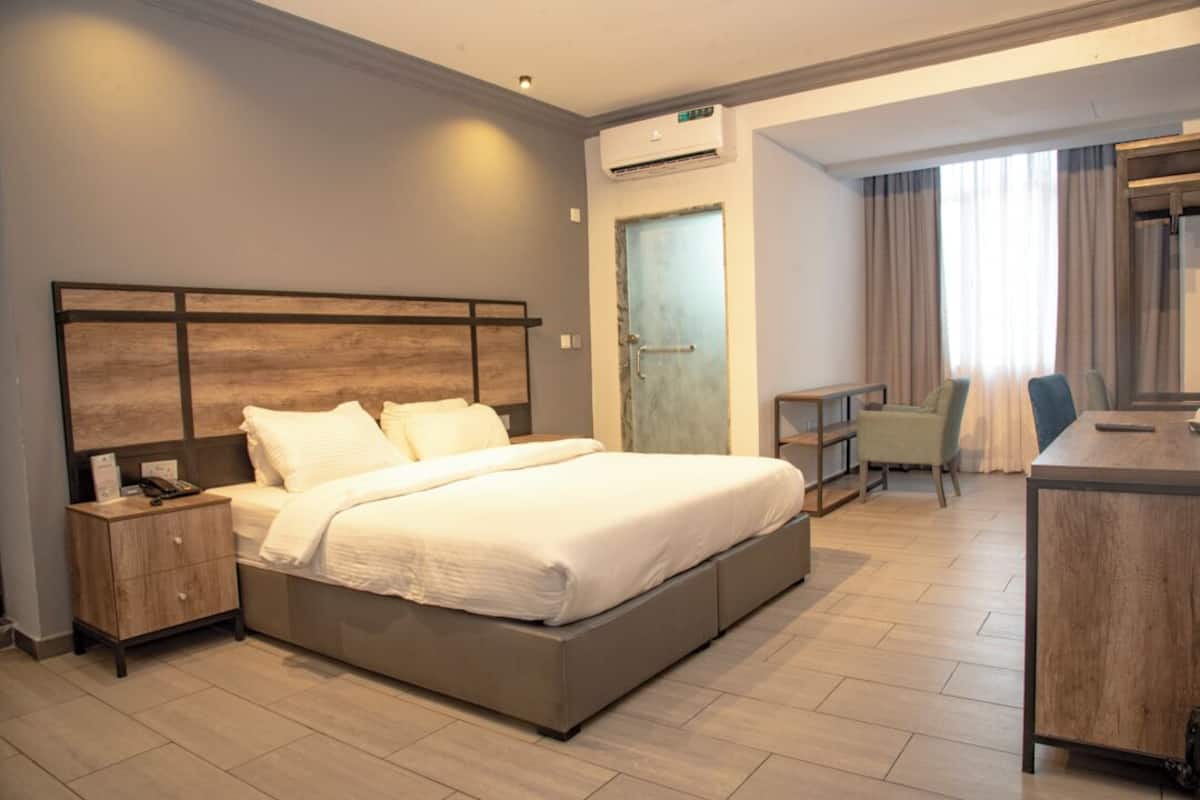 A modern hotel room with a large bed, bedside tables, a desk, and a chair.