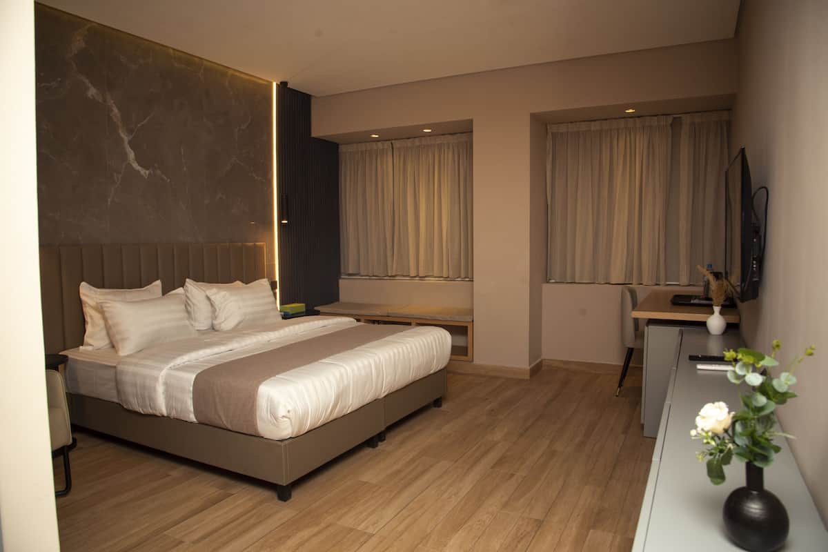 A modern hotel room with a large bed, a desk, and a television.