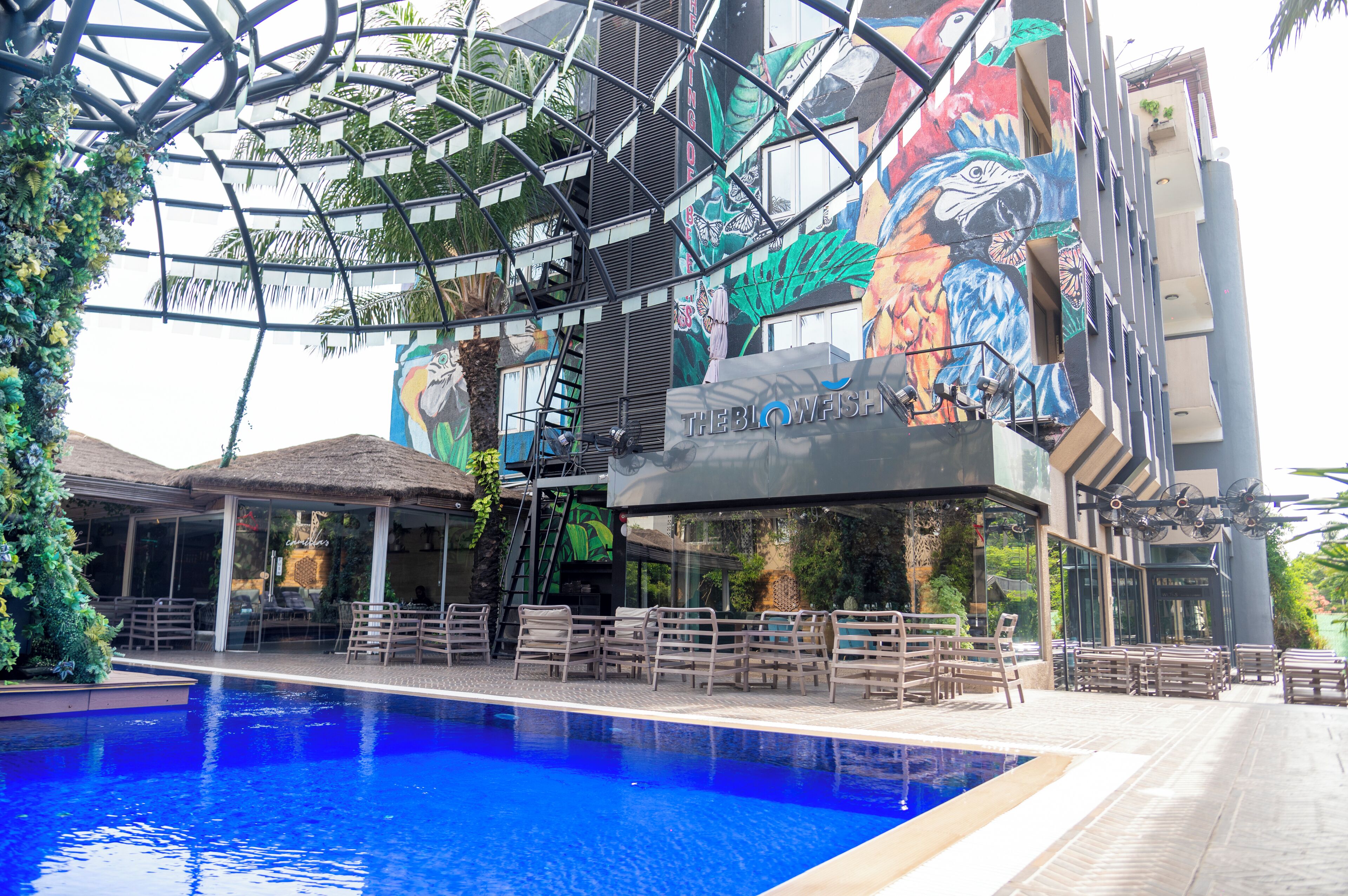 A hotel with a swimming pool, outdoor seating, and a colorful mural.
