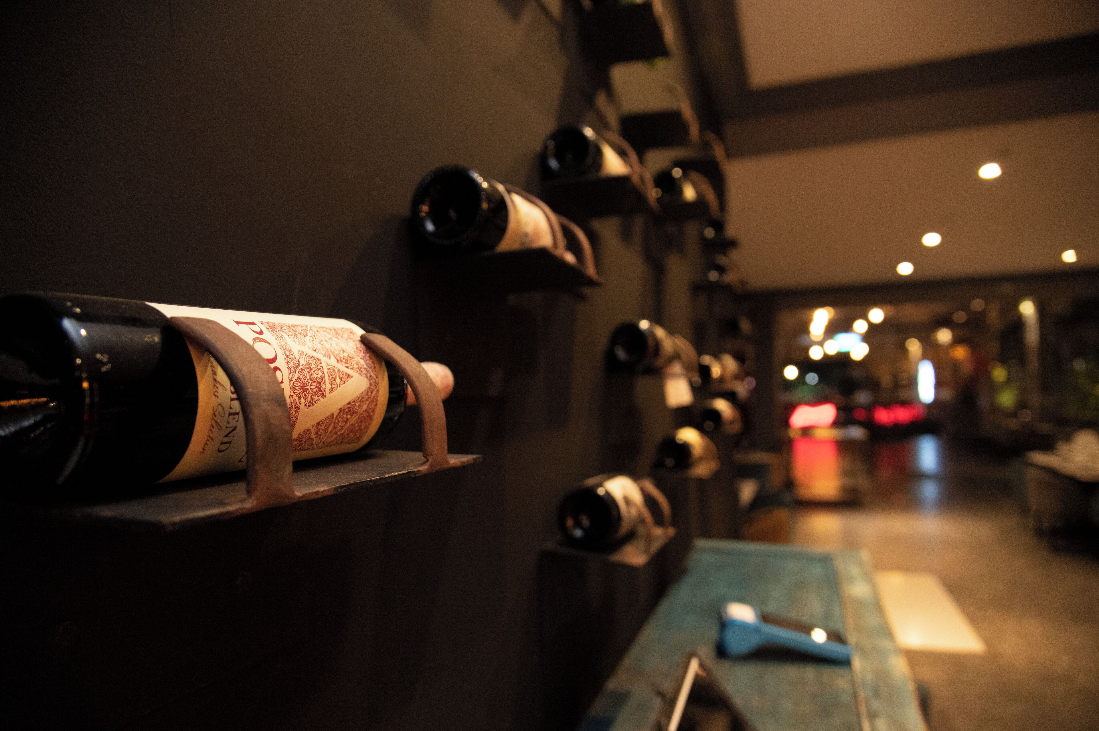 A wine rack with bottles and a wooden table with a knife.