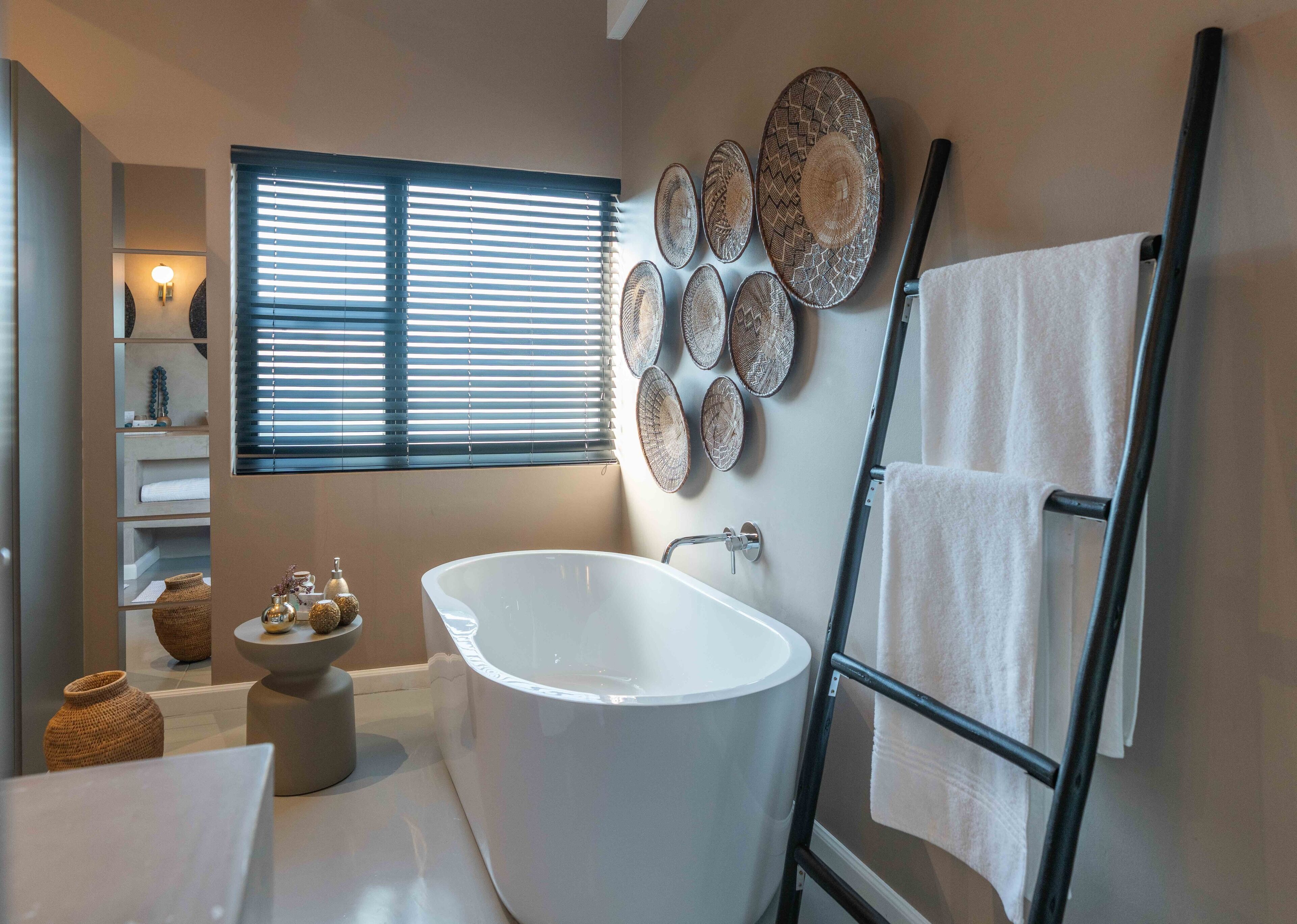 Une salle de bain moderne avec une baignoire sur pieds, un meuble-lavabo avec un miroir et une fenêtre avec des stores.