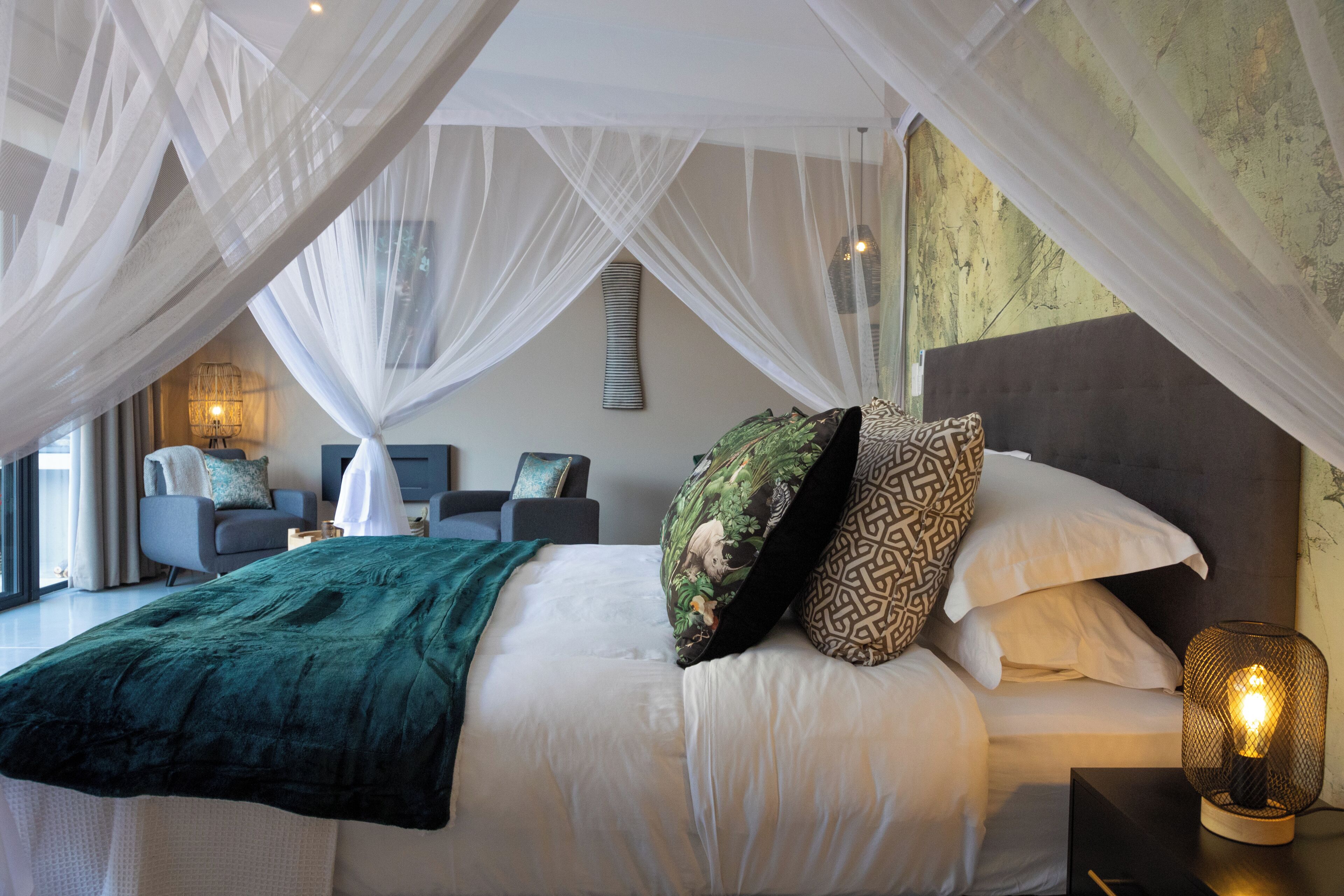 Une chambre à coucher avec un lit, une table de chevet, une lampe et une vue sur l’extérieur.