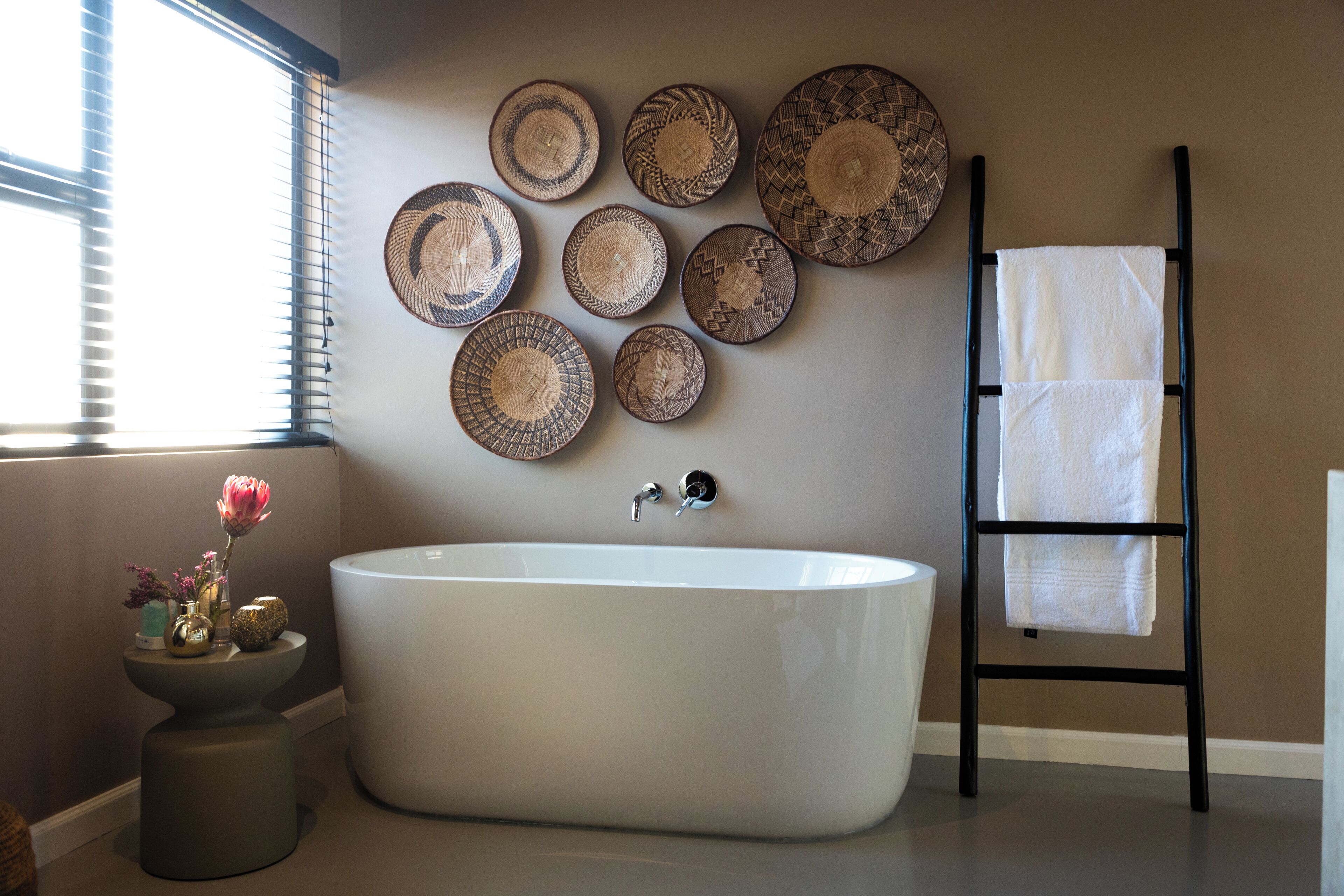 A modern bathroom with a freestanding bathtub, decorative plates on the wall, and a towel rack.
