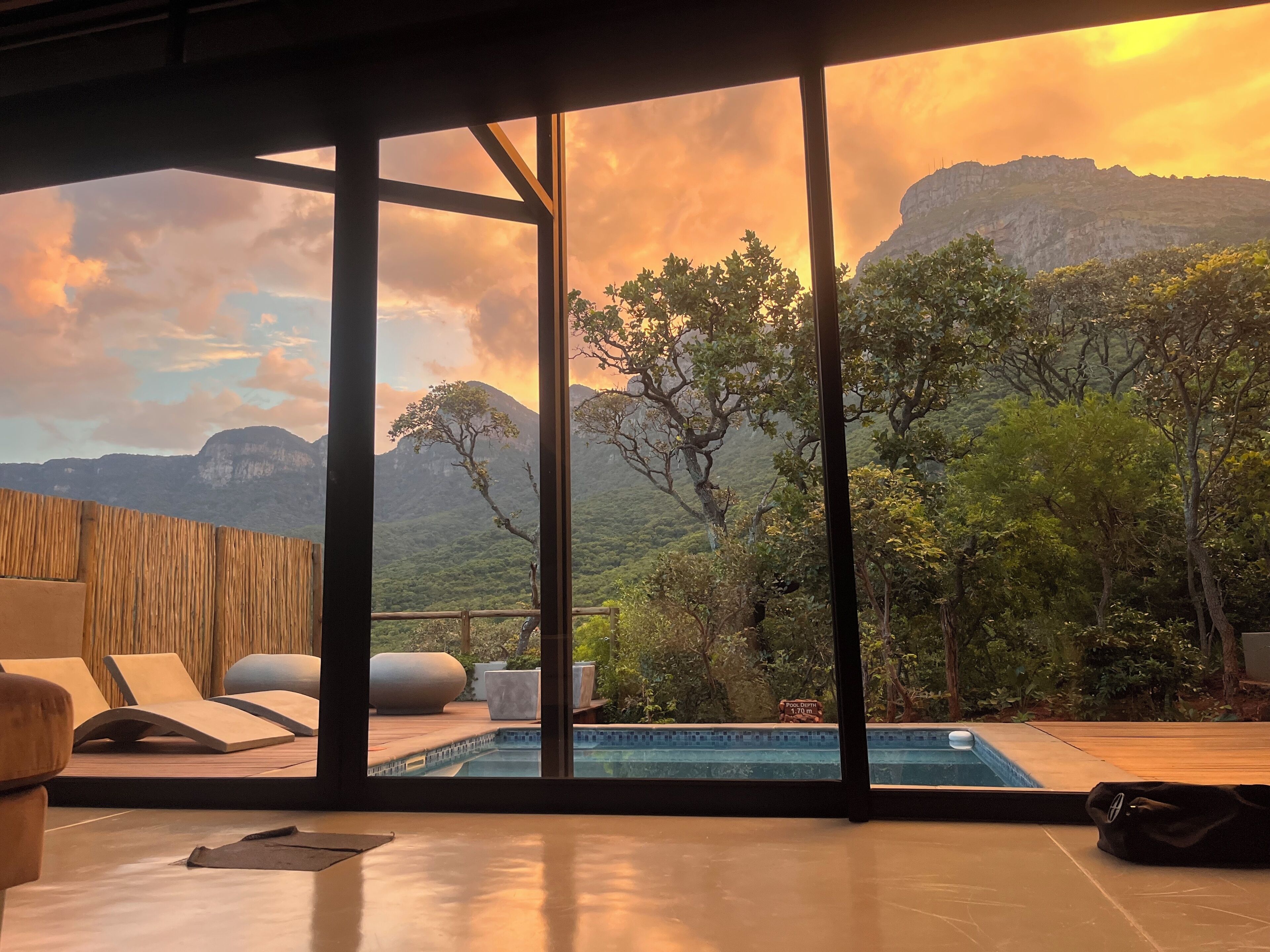 A modern room with a large window overlooking a pool and mountains.