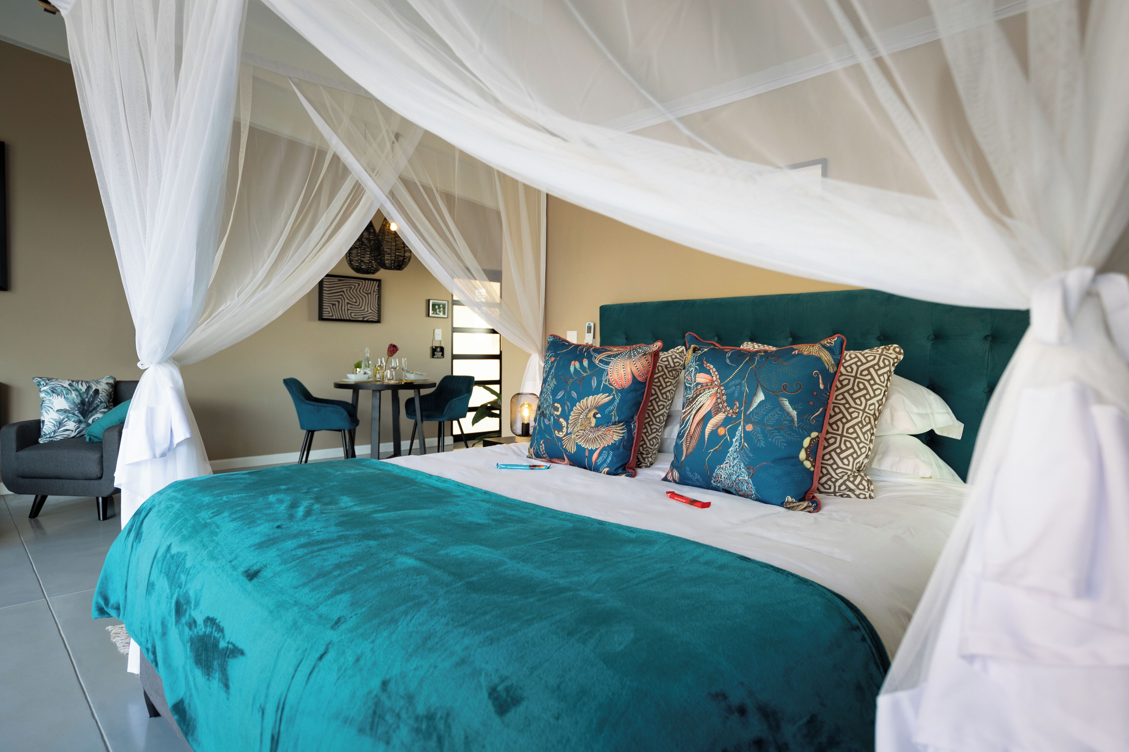 A spacious bedroom with a large bed, a green upholstered headboard, and a canopy bedspread.