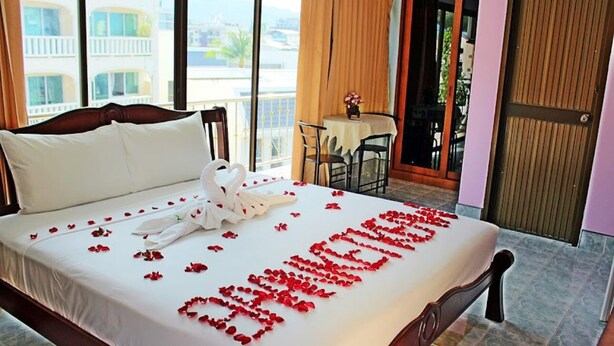 A hotel room with a bed, a table with chairs, and a balcony with a view. - BAAN KETKAEW GUEST HOUSE 2 (Patong)