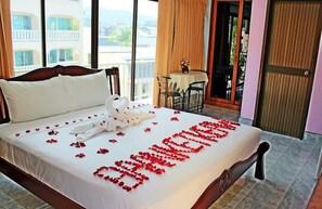 A hotel room with a bed, a table with chairs, and a balcony with a view. - BAAN KETKAEW GUEST HOUSE 2 (Patong)