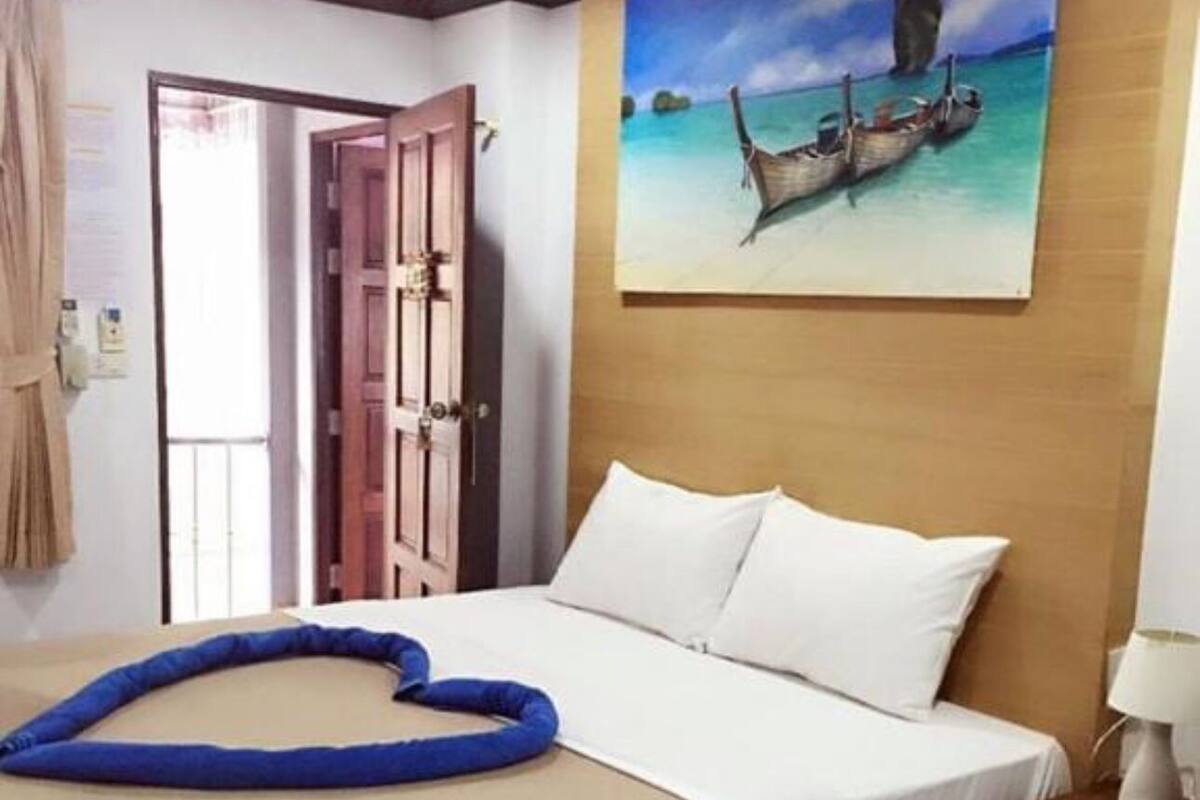 Une chambre d’hôtel avec un lit, un tableau représentant des bateaux sur l’eau, une tête de lit en bois et une table de chevet avec une lampe.