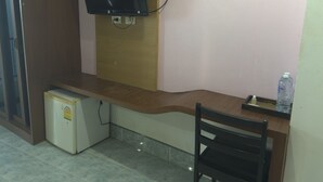 A small kitchenette with a refrigerator, a microwave, and a wall-mounted television. - BAAN KETKAEW GUEST HOUSE 2 (Patong)