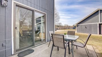 Een modern gebouw met een schuifdeur die uitkomt op een terras met een tafel en stoelen.