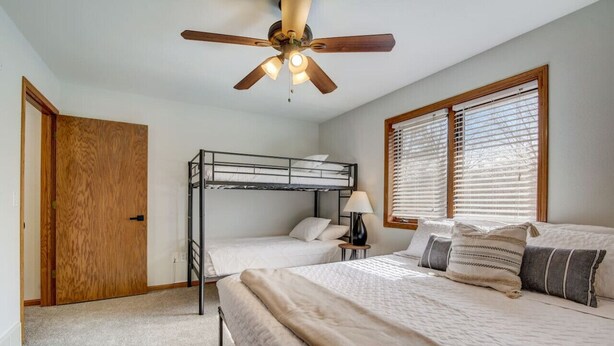 A bedroom with a bunk bed, a single bed, a ceiling fan, and a window with blinds. - Peyton's Place at Tamarack - Great Location! (Wisconsin Dells)