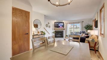 Un salón comedor amplio con chimenea, una zona de estar acogedora con sofá y sillones, y un espacio de comedor con una mesa grande.