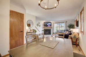 A spacious living room with a fireplace, a dining area with a large table, and a cozy seating area with a sofa and chairs. - Harrison's Hideaway at Tamarack - Great Location! (Wisconsin Dells)