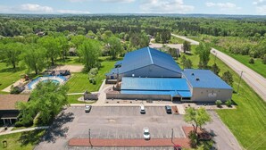 Un grand bâtiment doté d’un toit bleu, entouré d’un parking et d’une piscine.
