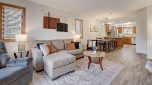 A living room with a sofa, armchairs, a coffee table, and a dining area with a table and chairs.