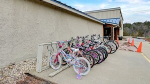 Une rangée de vélos garés contre un mur, l’entrée d’un immeuble et un ciel dégagé.