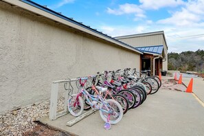 A row of bicycles parked outside a building with a concrete floor and a gravel path. - Harrison's Hideaway at Tamarack - Great Location! (Wisconsin Dells)