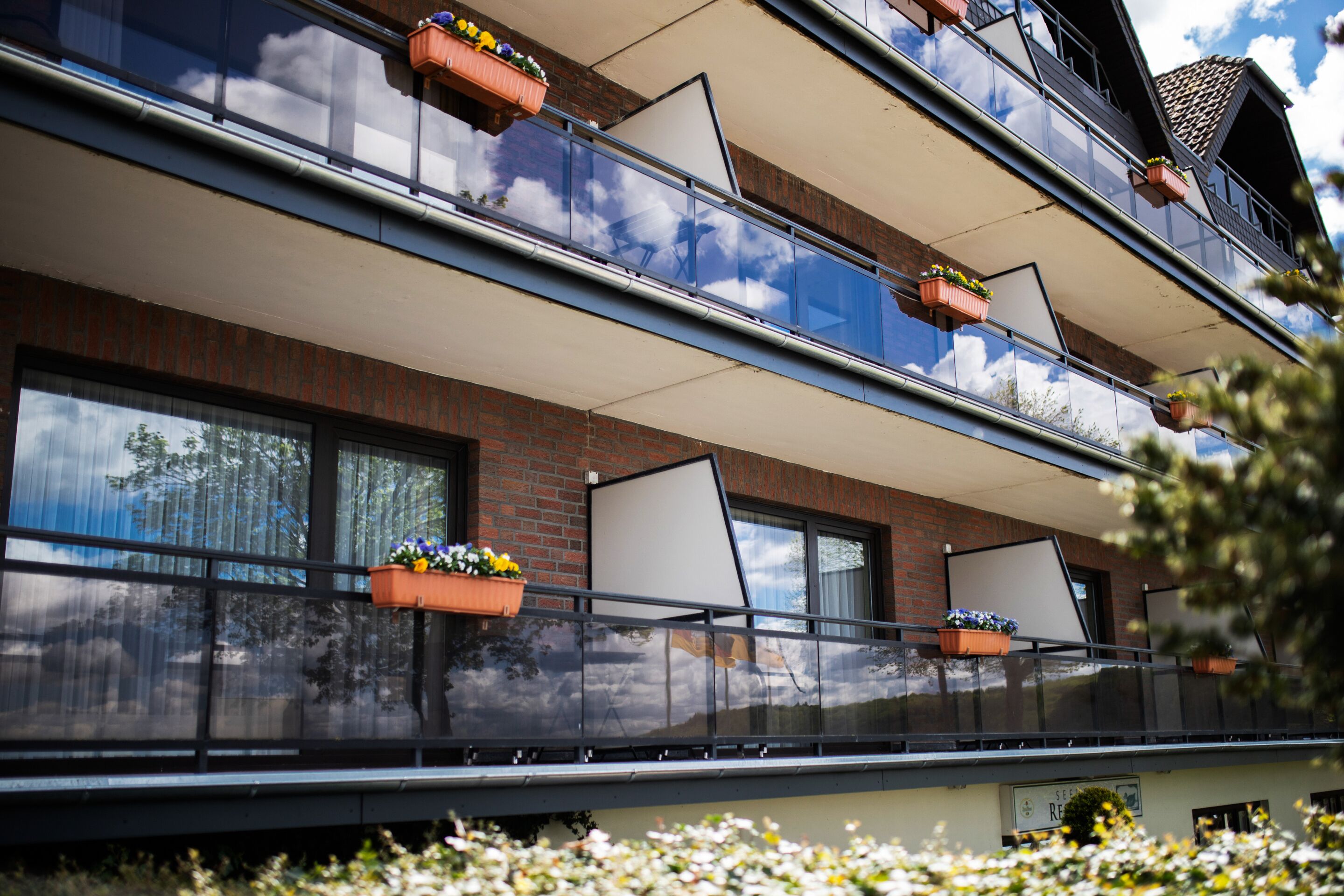 A multi-story building with balconies, large windows, and flower boxes.