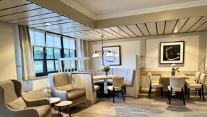 A modern hotel room with a dining area, a sofa, and a table with chairs. - Landhuus Dieksee (Malente)