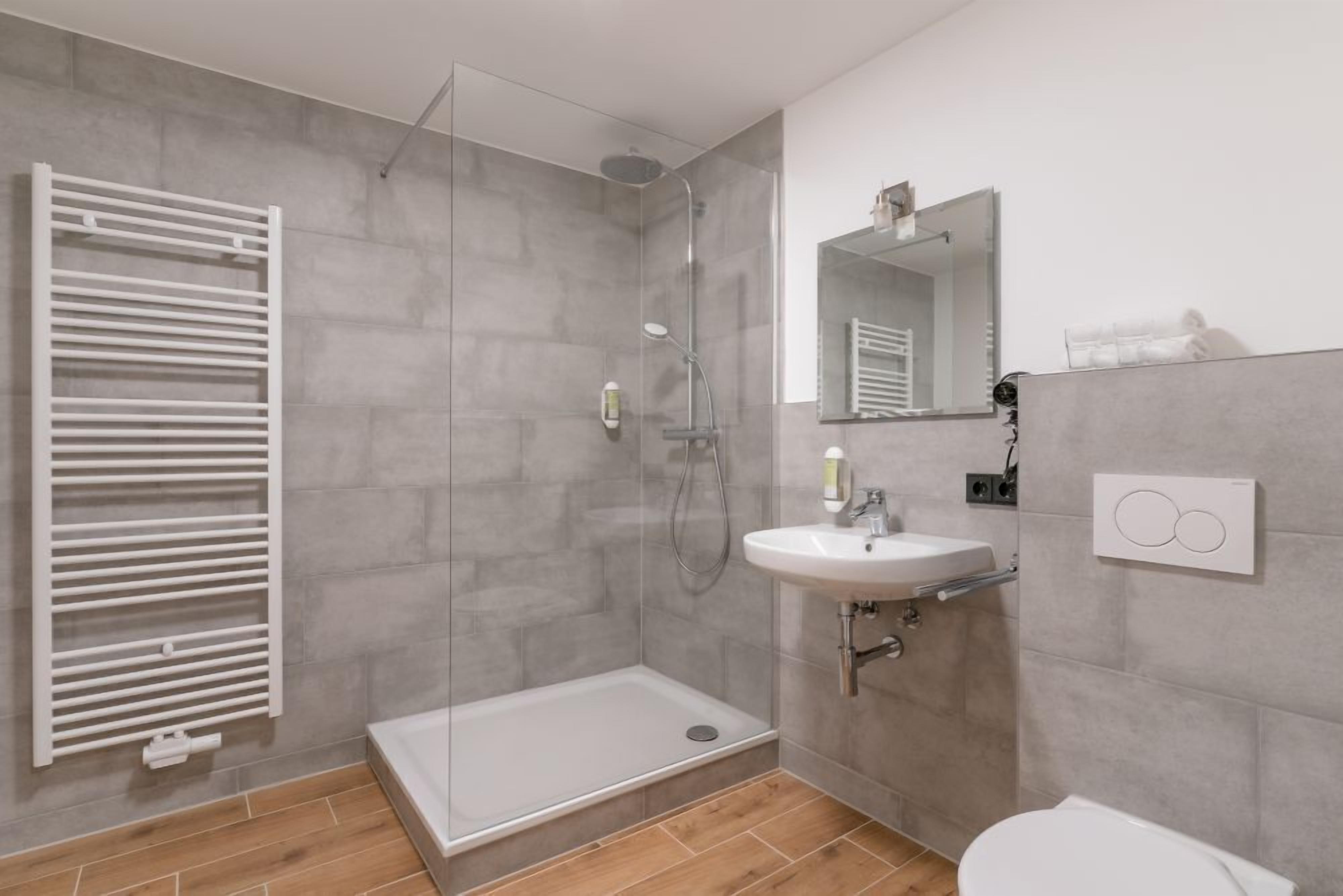 Une salle de bain moderne avec une douche à parois de verre, un lavabo blanc et des toilettes.