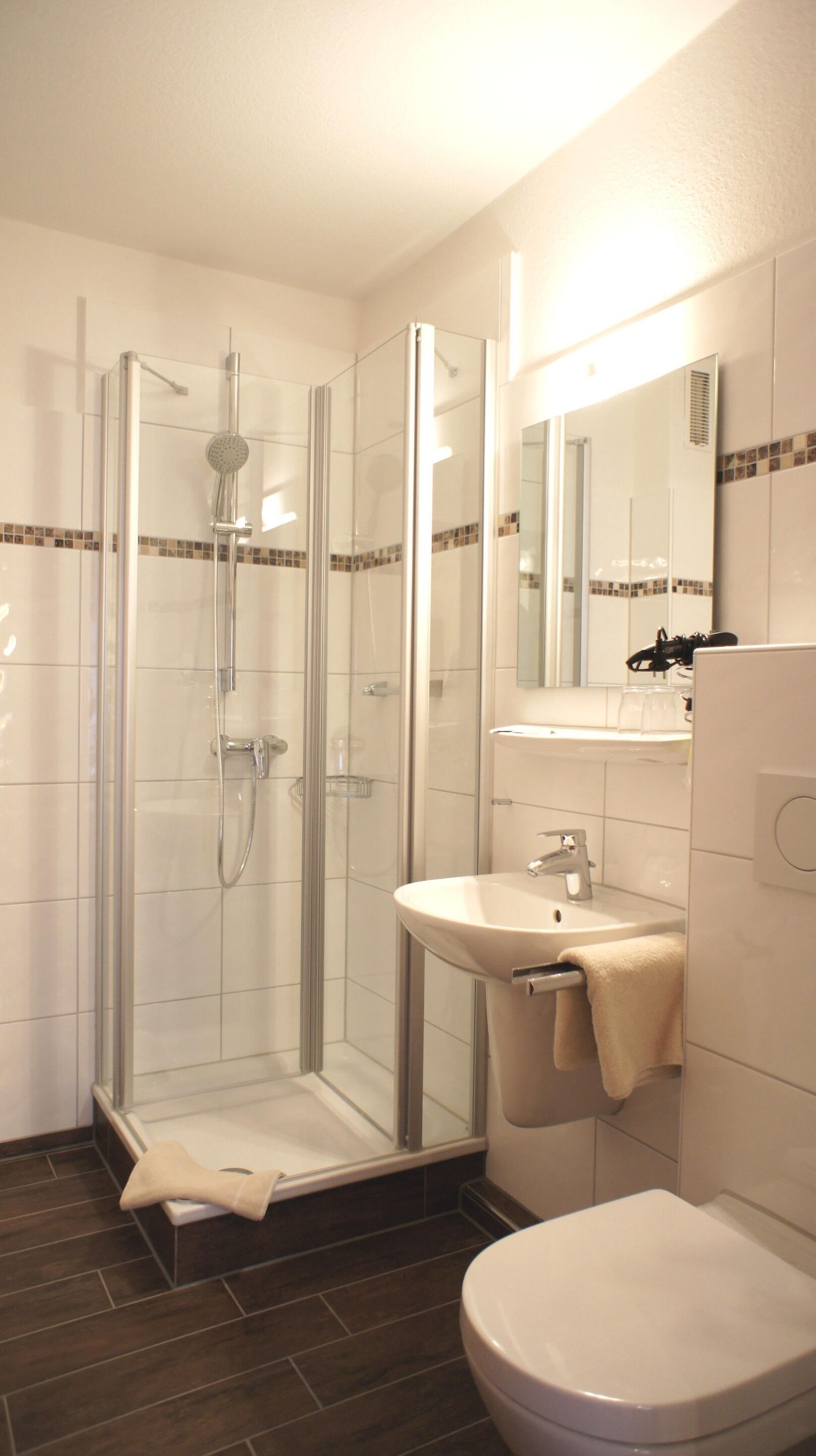 Ein modernes Badezimmer mit einer Duschkabine, einem weißen Waschbecken und einer Toilette.