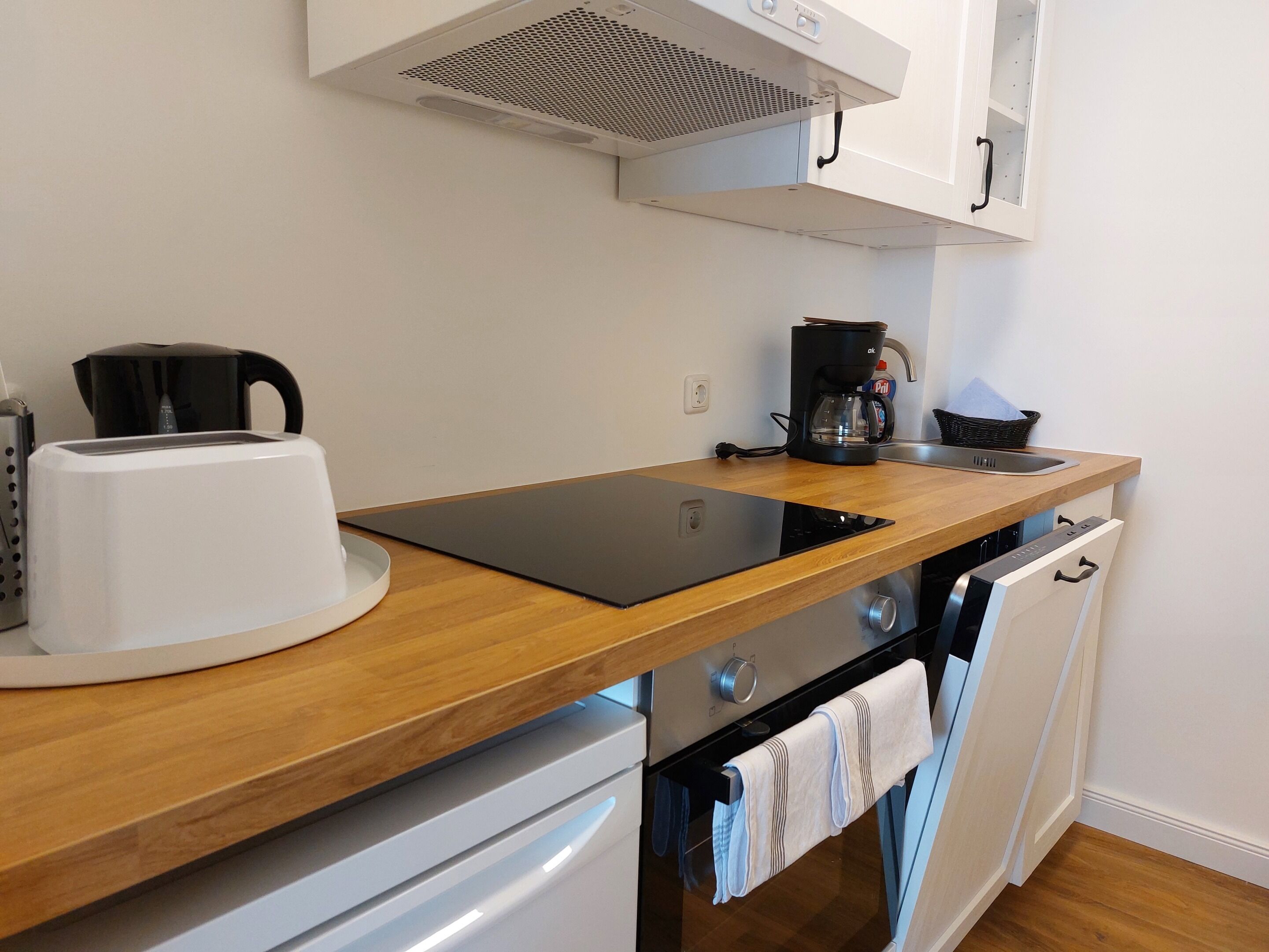 Una cocina compacta equipada con tostadora, cafetera, hervidor y lavavajillas.