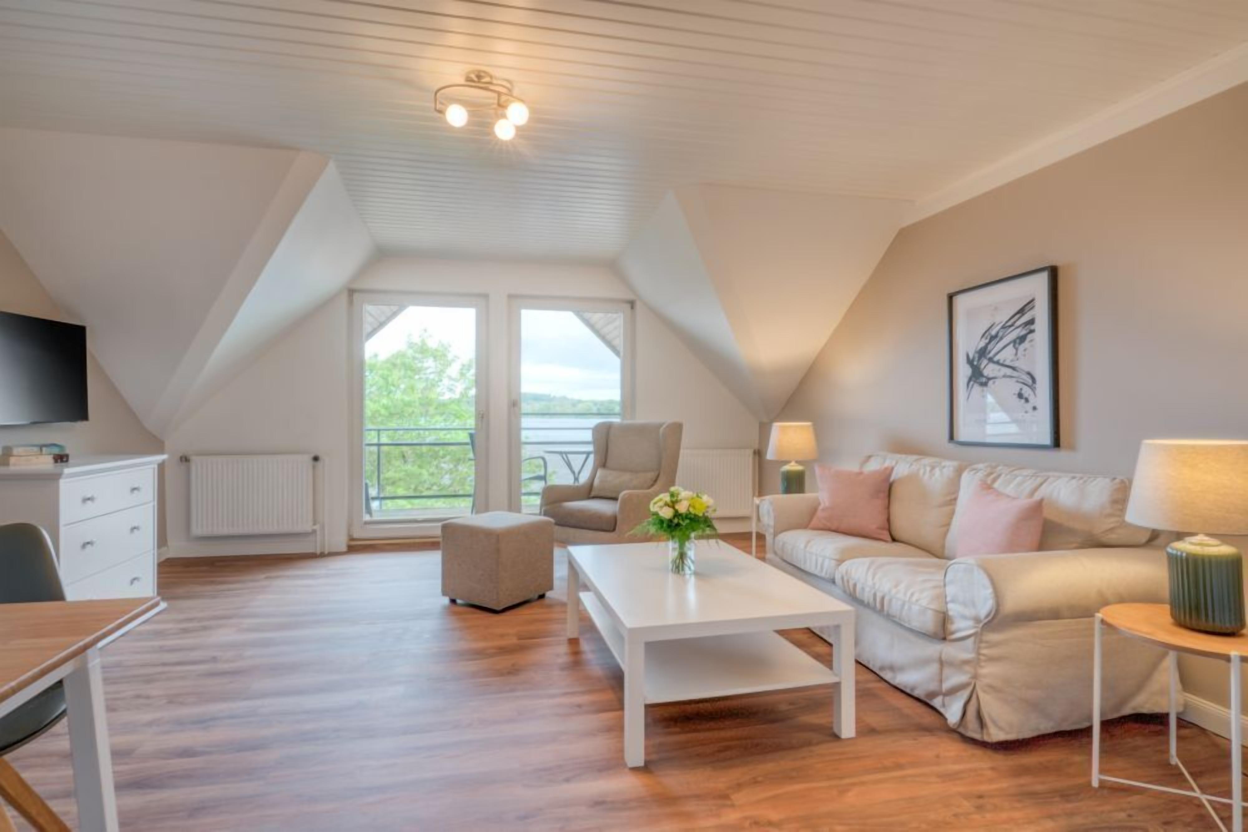 Un espacioso dormitorio tipo loft con un gran ventanal, techo blanco y diseño moderno.