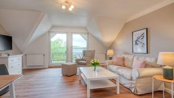 Un espacioso dormitorio tipo loft con un gran ventanal, techo blanco y diseño moderno.