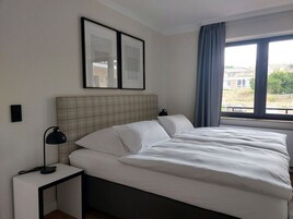 Una habitación de hotel con una cama, una mesita de noche, una lámpara y una ventana con cortinas.