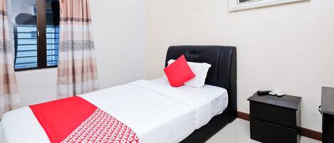 A bedroom with a bed, a nightstand, a window with curtains, and a painting on the wall.