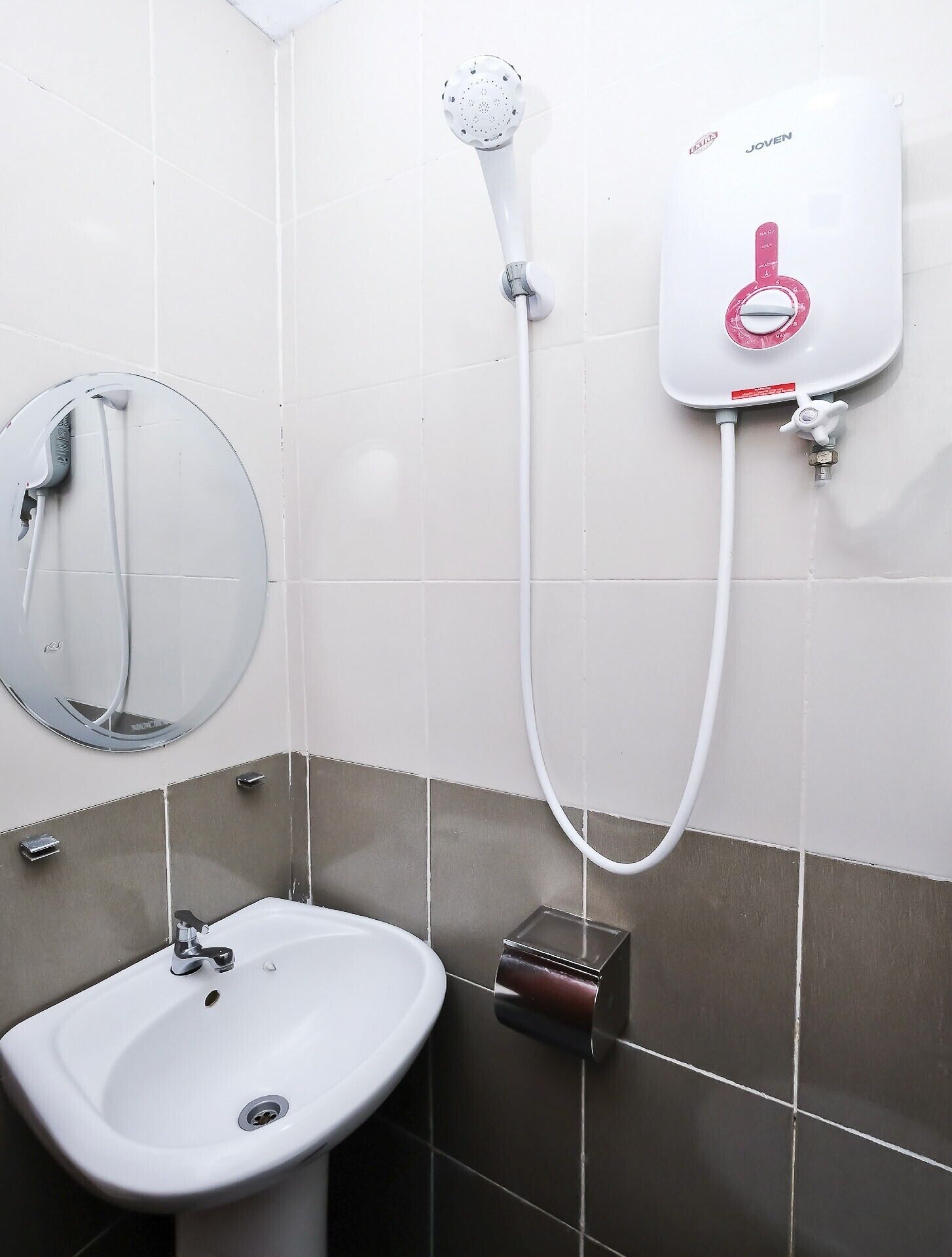 Ein Badezimmer mit Waschbecken in Weiß, einer Handbrause und einem an der Wand montierten Boiler.