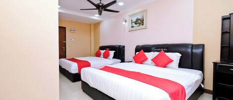 A hotel room with two beds, each with white bedding and red accents, a ceiling fan, a painting on the wall, and a black nightstand.