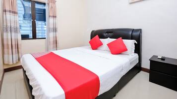 A neatly made bed with a white and red bedspread, a black headboard, and two red pillows.